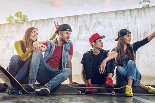 Grupa młodych osób ze skateboardami jako przykład subkultury młodzieżowej